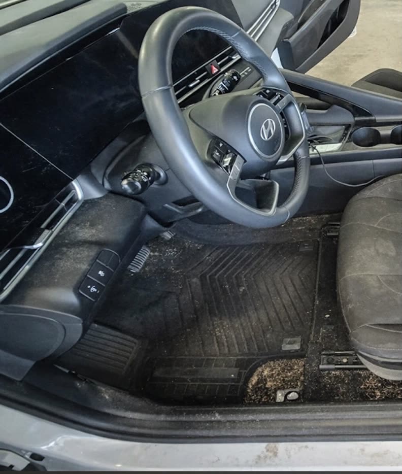 A Hyundai Elantra interior before detailing — mud-caked floor mats and dirty, stained carpet