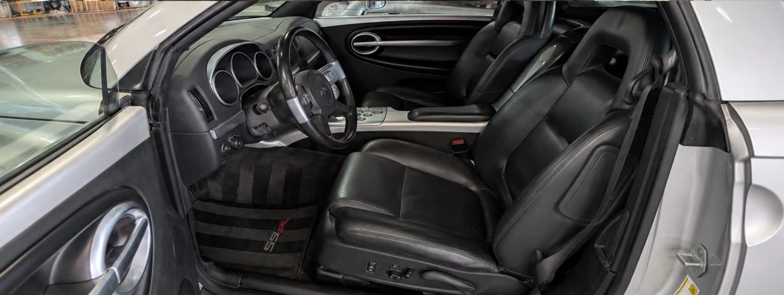 The same convertible interior after cleaning — carpet cleaned and black leather conditioned