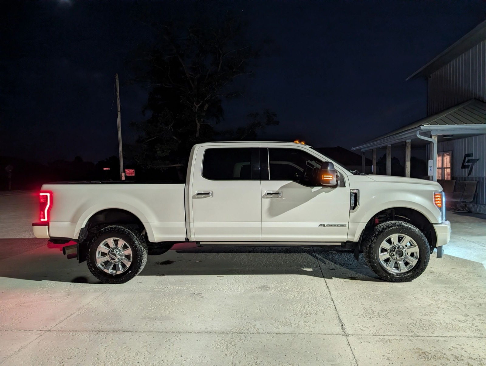 A white Ford Super Duty photographed side-on at night after detailing