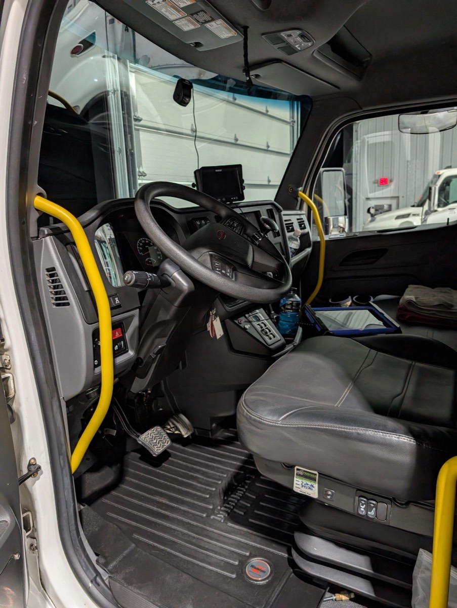 The cleaned cab interior of a commercial box truck, showing the steering wheel, seat and floor