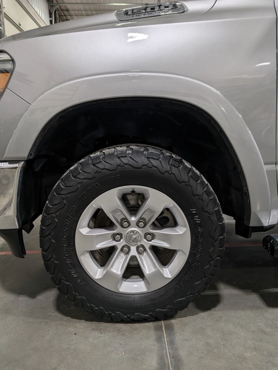 A close-up of a cleaned alloy wheel and dressed tire on a detailed SUV
